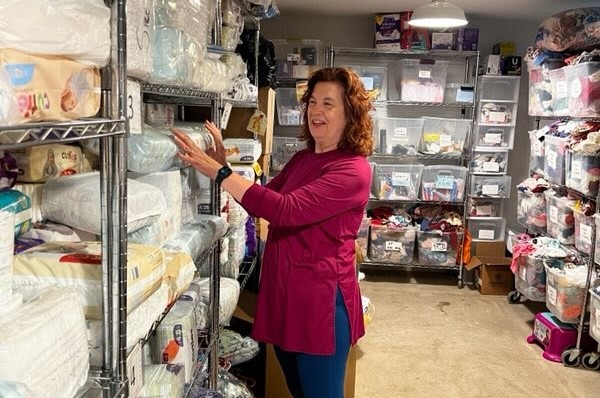 Woman in a pink shirt standing in front of shelves of baby diapers