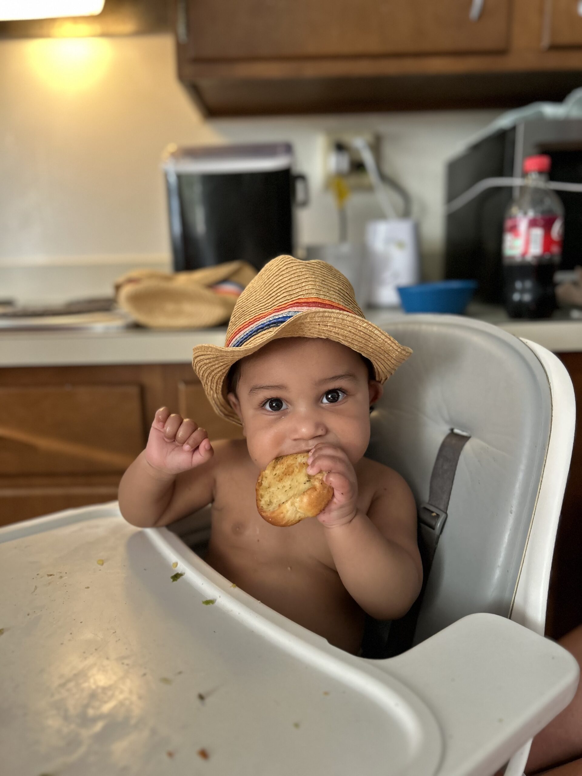 baby wearing a hat sitting in high chair