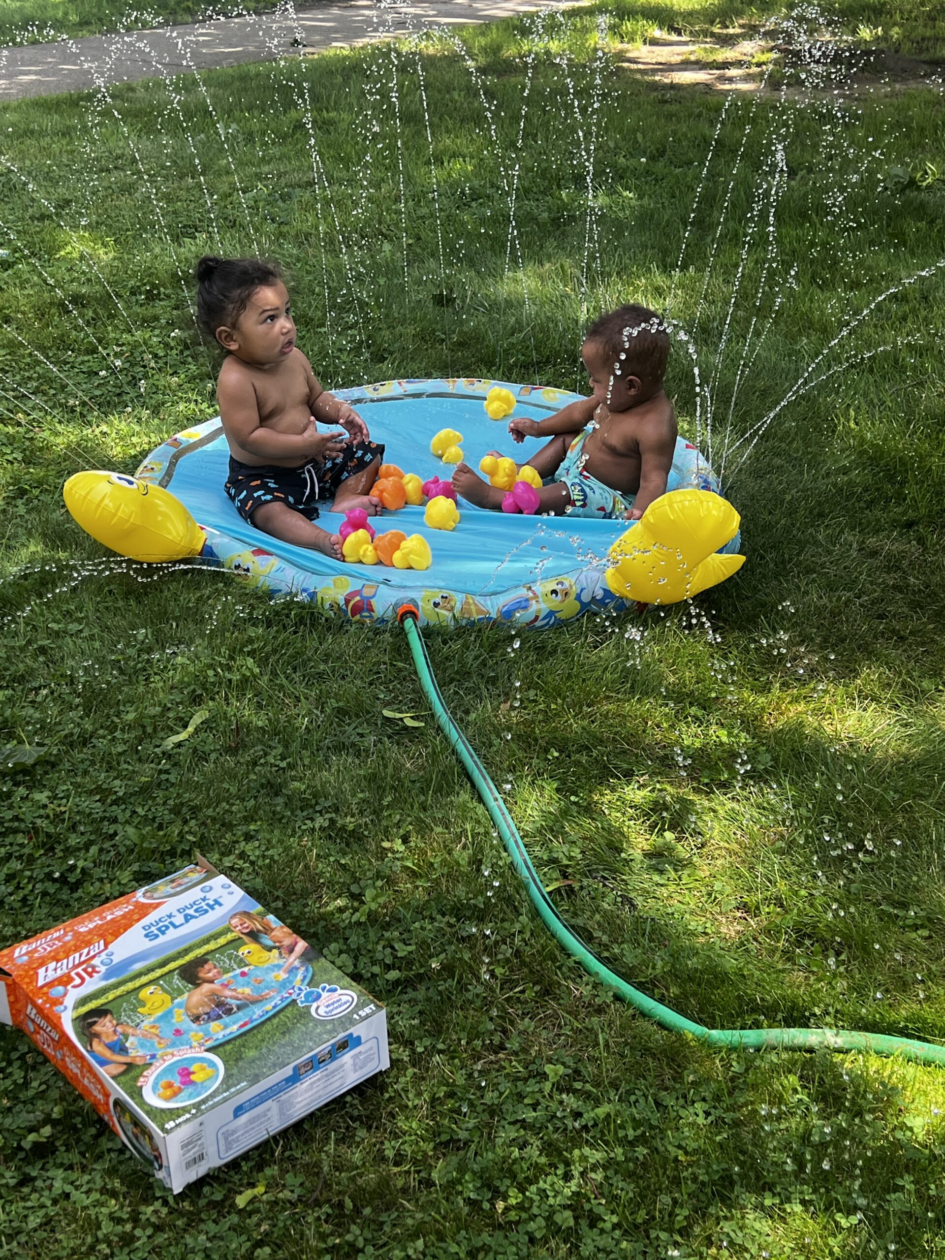 two toddler boys playing on splash pad
