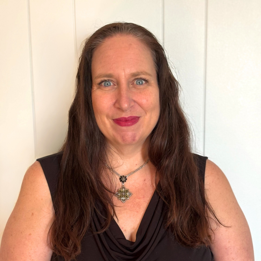 Wendy Wright, a white woman with long dark hair and red lipstick wears a necklace and black blouse agatest a white background