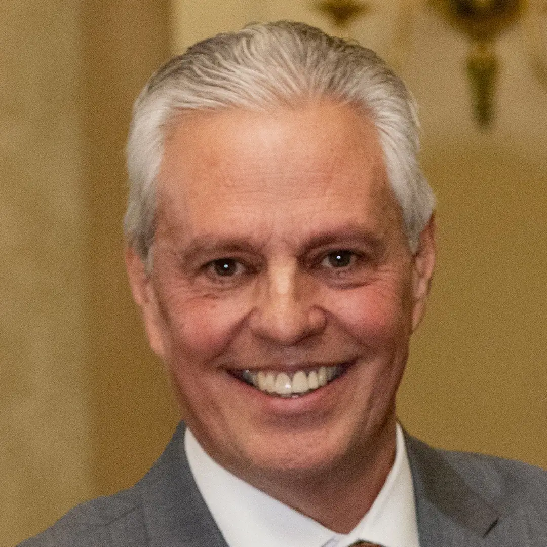 Michael S. Cudwadie, a white man with grey hair and a grey suit smiling for a portrait