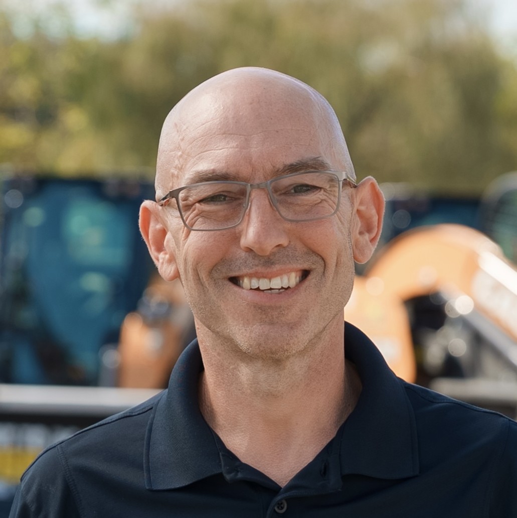 Bob Marks, a bald middle-aged white man with glasses smiles while outdoors